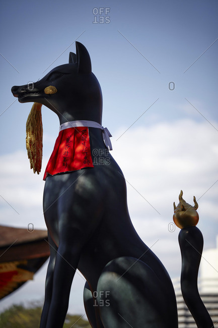 Statue of a black fox with a key at the Fushimi Inari Taisha shrine in Kyoto, Japan