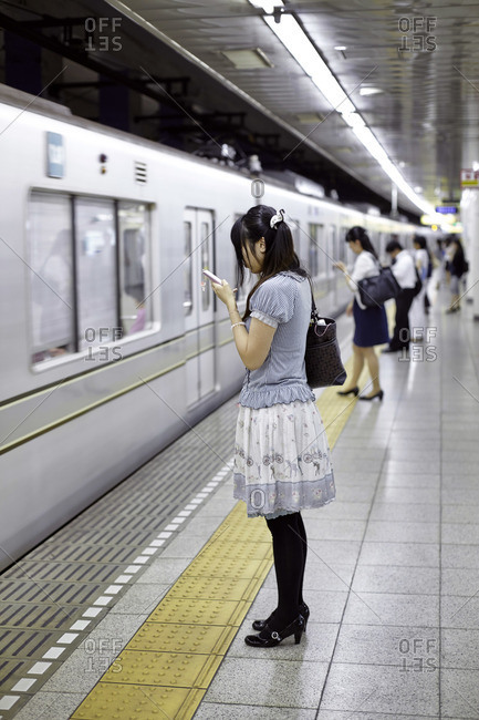Young woman standing at a subway station in Tokyo, Japan