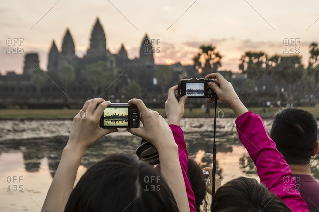 Tourists photographing the sunrise over the west entrance to Angkor Wat, Siem Reap, Cambodia