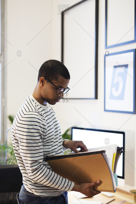 Young creative man with files in his home office