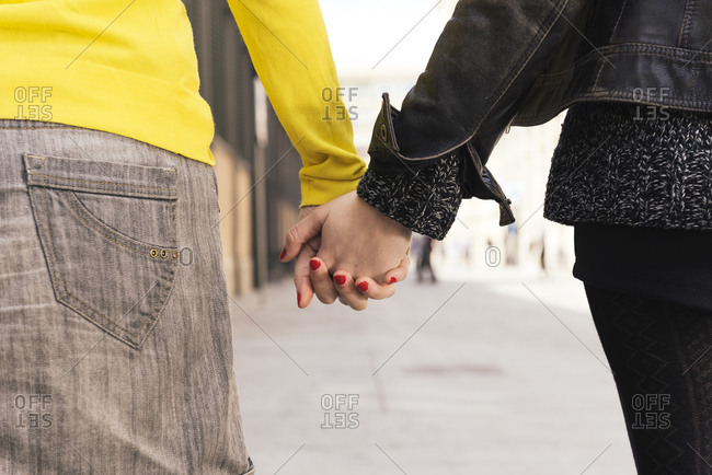 Two women holding hands on the street