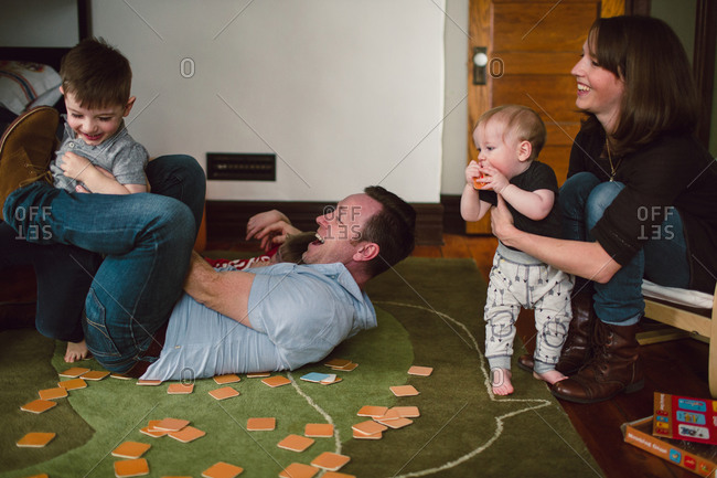 Parents wrestling with children in bedroom