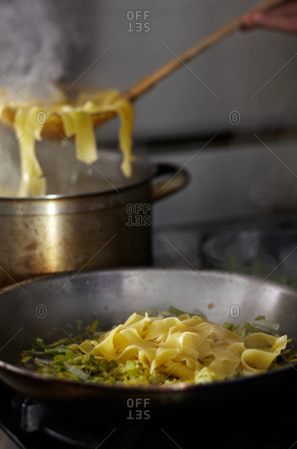 Cooked pasta being added to a skillet