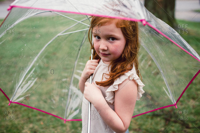 A little girl under a bucket umbrella