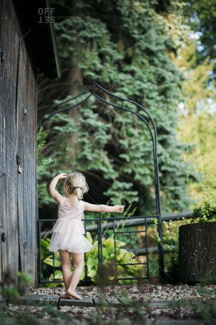 Little girl practicing ballet positions next to a backyard shed