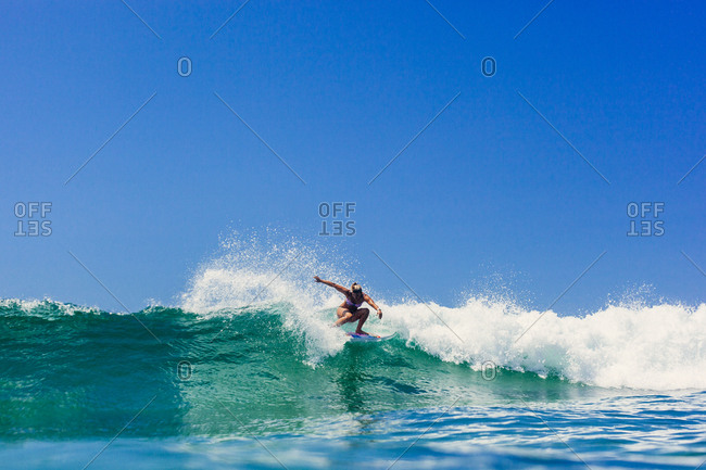 A surfer crouches while riding a wave