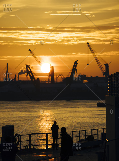 Silhouettes of harbor cranes at sunset with the Koehlbrand bridge in the background