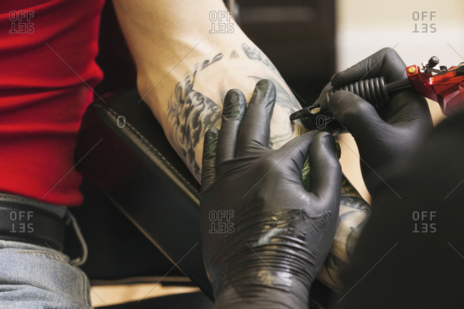 Tattoo artist at work on customer\'s forearm