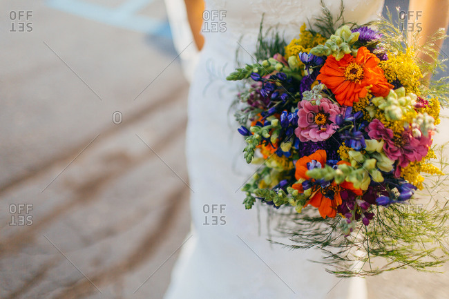 A bride carries a brightly colored bouquet