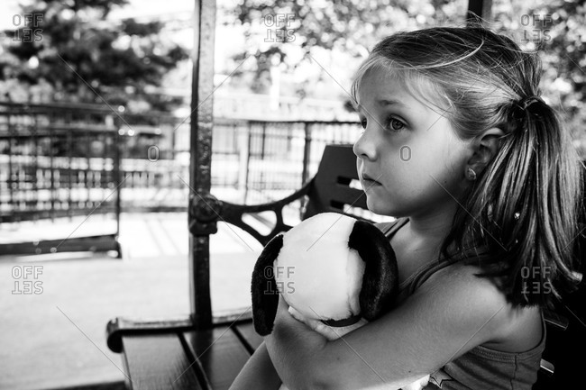 Young girl hugging a stuffed animal on a bench