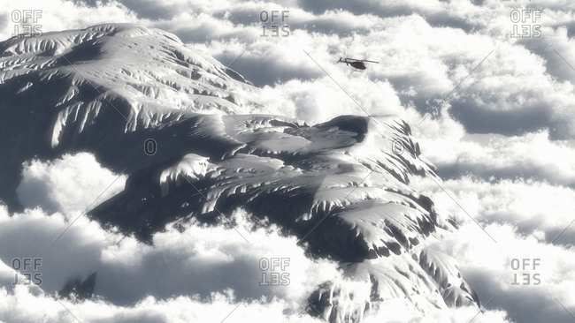 A helicopter flies over a snow covered mountain