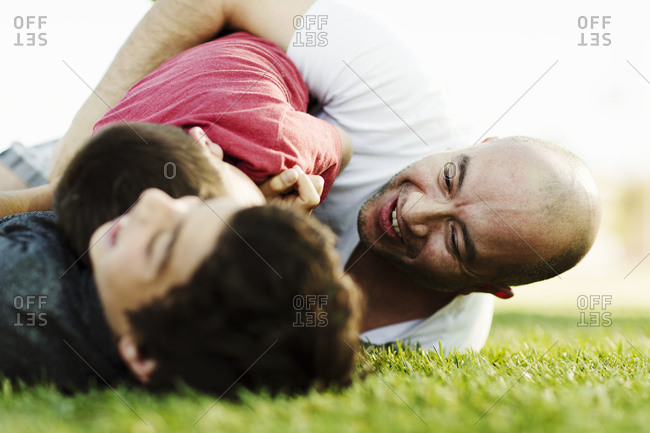 Father wrestling sons on the grass