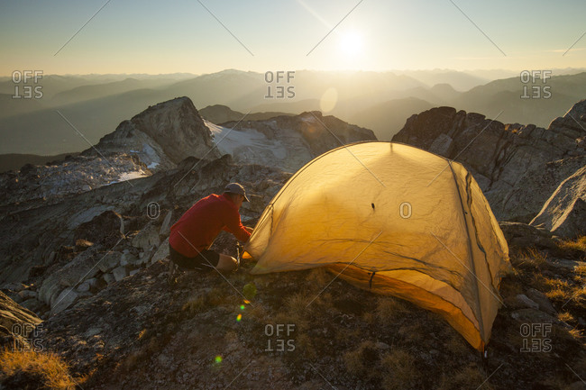 A hiker sets up a tent on the summit of Saxifrage Peak, Pemberton, BC, Canada