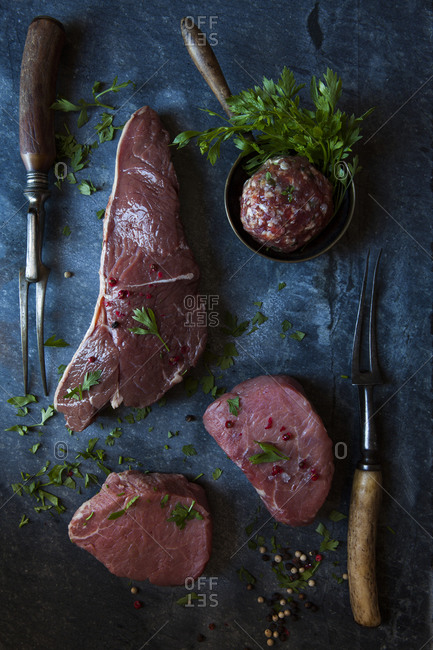 Overhead view of different cuts of beef on a slate background