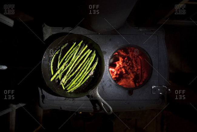 A pan of asparagus being cooked on a wood stove