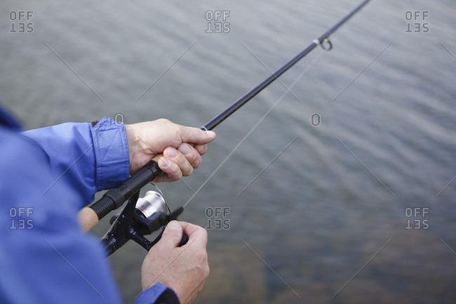 Close-up of a man\'s hands holding a fishing pole