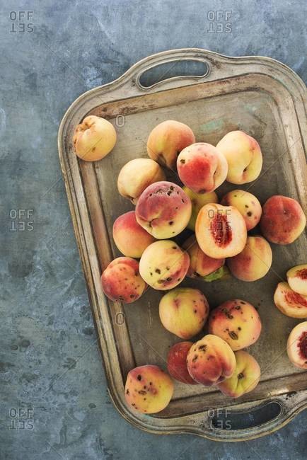 Overhead view of mottled peaches on a silver tray