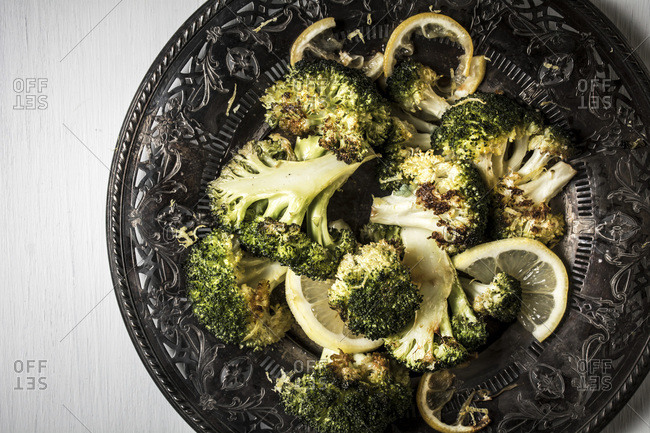 Roasted broccoli and lemon on a dark plate