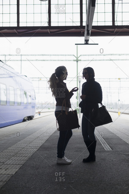 Two young women conversing at a train station