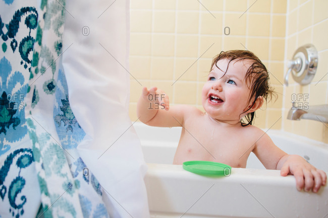 A toddler plays with a shower curtain