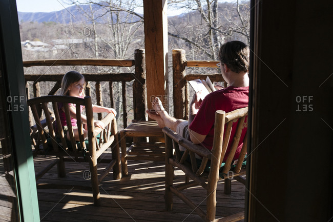 Girl and man hanging out on rustic porch