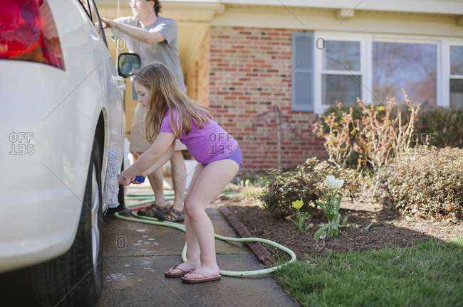 Girl and dad washing car in driveway
