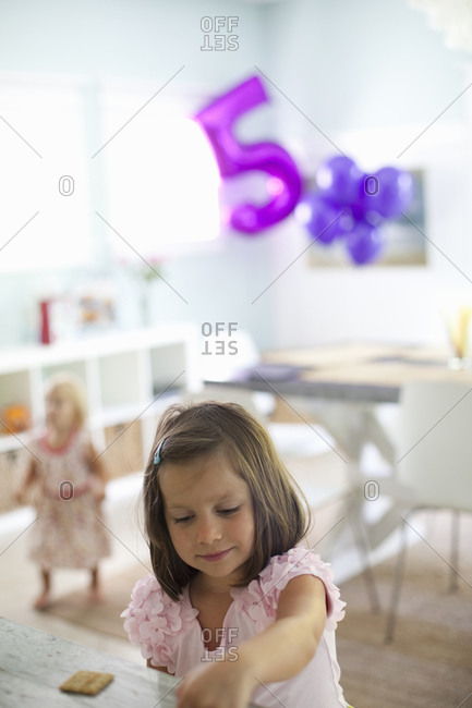 Young girl in a pink shirt with balloons in background