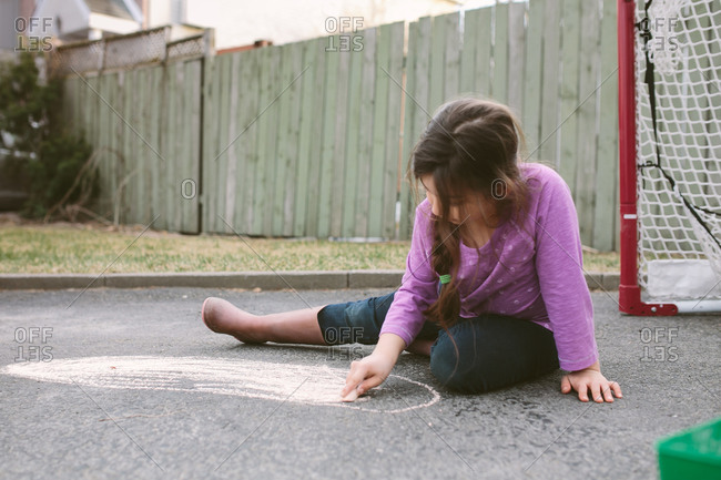 Young girl drawing on pavement with chalk