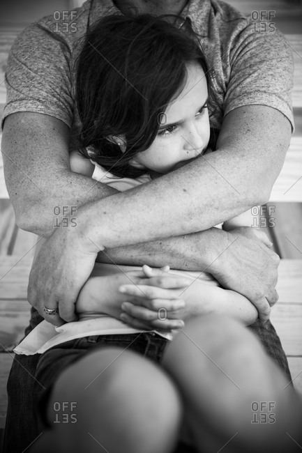 A girl leans back on her father\'s lap