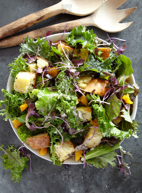 Overhead view of a green salad with croutons, pea shoots and orange sections