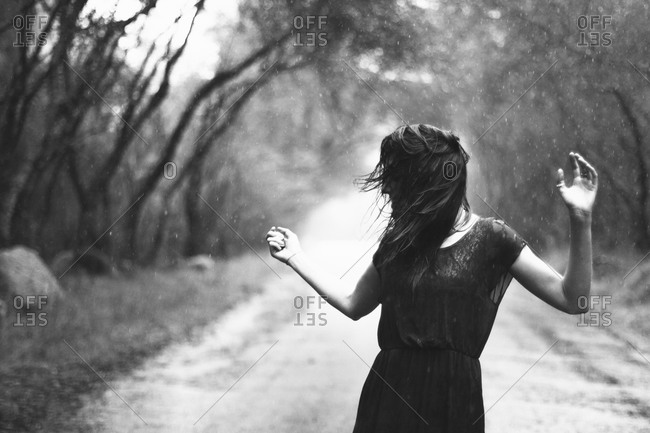 Woman carefree in rain on country road
