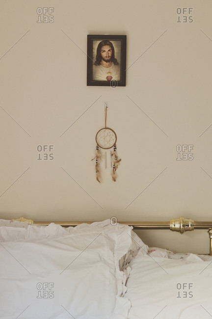 Portrait of Jesus and a dream catcher hang on the bedroom wall behind the bed
