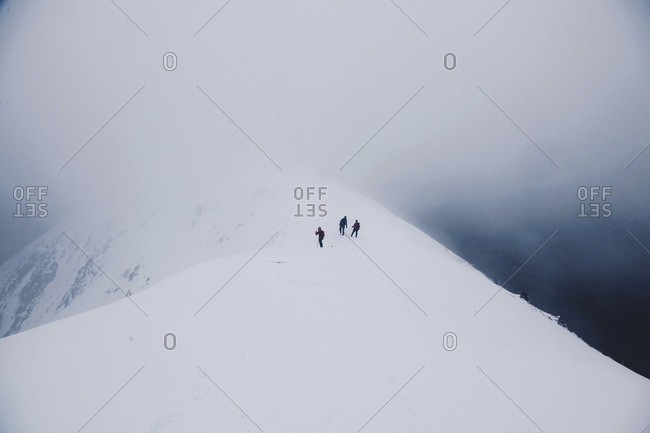 A trio of mountain climbers on a snow-capped mountain