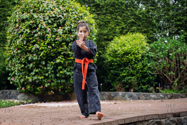 A girl in a karate uniform brings her palm to her fist