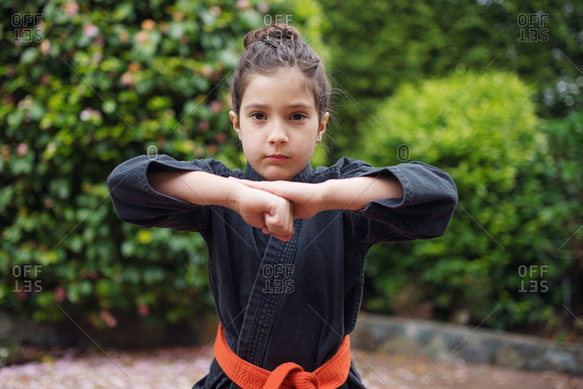 A girl in a karate uniform raises her fist to her chin
