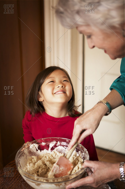 Girl smiling as woman mixes cookie dough