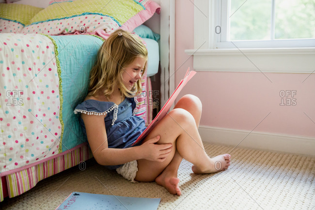 Young girl in pink bedroom looking at drawings