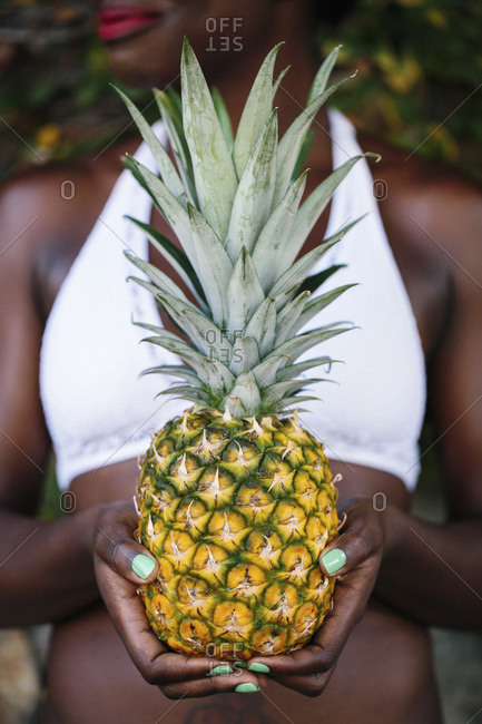 A Caribbean woman holding a fresh pineapple