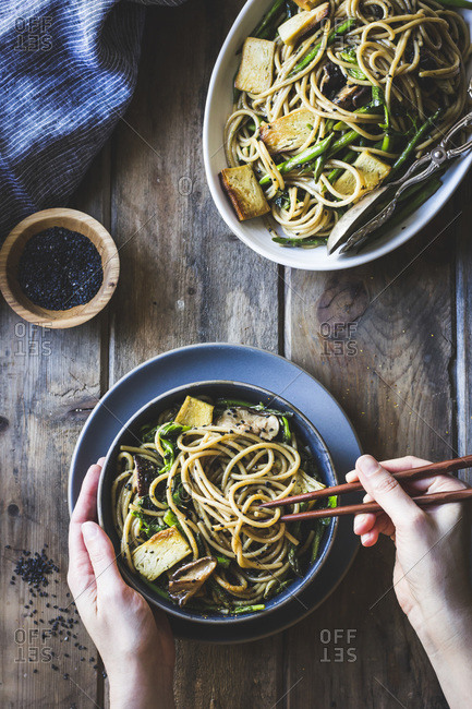 Eating sesame noodles with tofu and vegetables