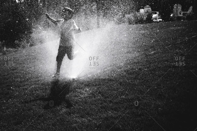 Boy runs through a sprinkler