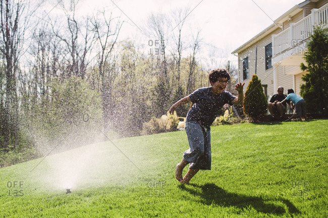 Boy runs through a sprinkler