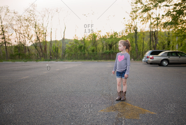 Girl standing in rural parking lot in summer