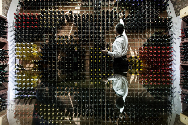 Wine steward pulling wine bottles from a wine cellar