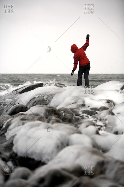 A woman balances on rocks covered in ice