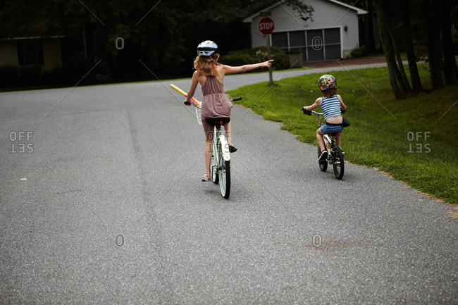 Older sister signals a turn while riding bikes with her brother