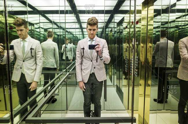 A man takes a selfie in a mirrored elevator
