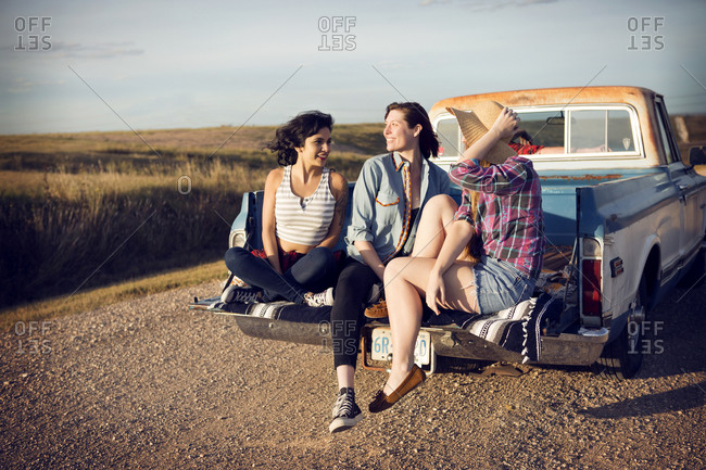 Friends sitting on truck hatch in country