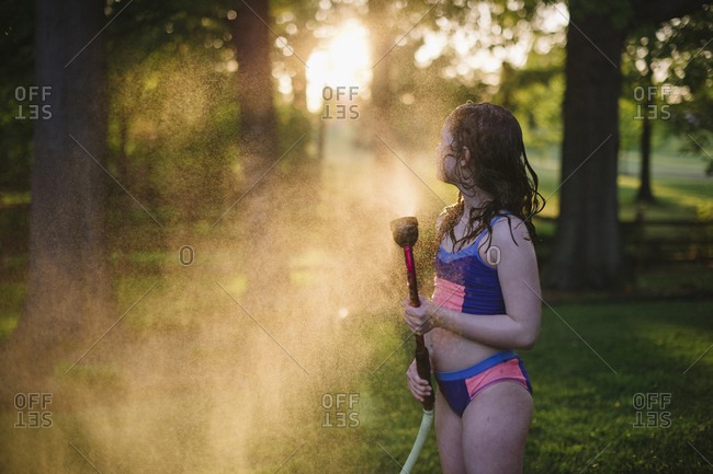 Girl standing in the mist from a garden hose