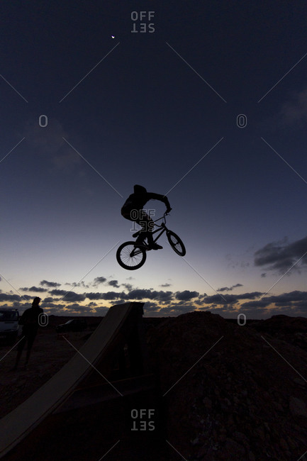 Silhouette of a person with bmx jumping at dusk