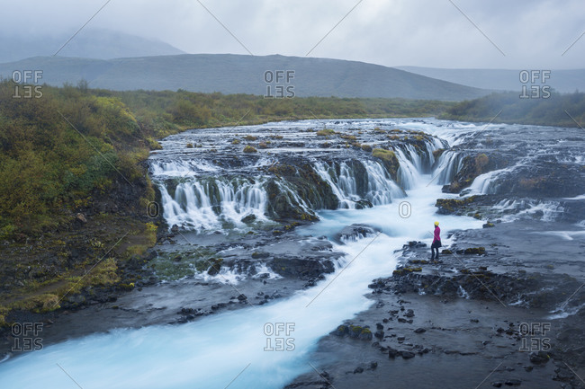 A visitor admires the unique waterfall near the Golden Circle attractions known as Brœarfoss in Iceland